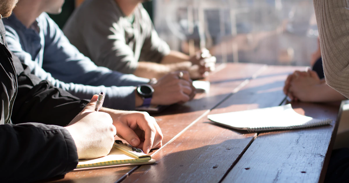 People seated at a table during a meeting with documents and pens